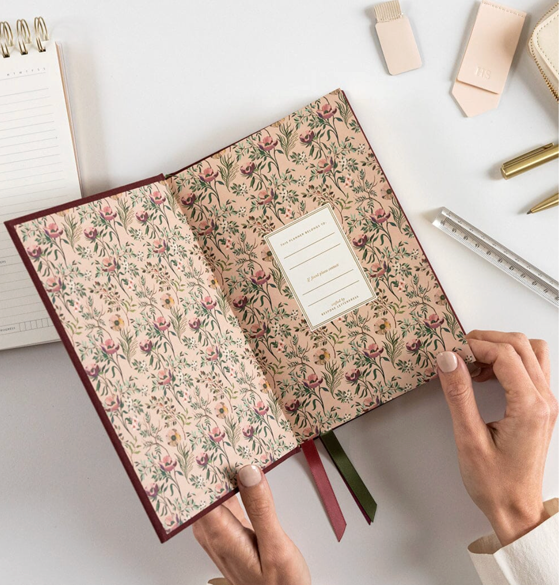 Floral-patterned notebook with hands holding it on a light background
