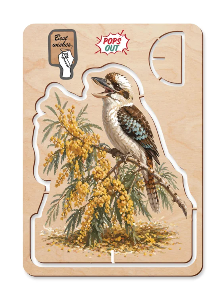 A wooden bird puzzle featuring a kookaburra perched on a yellow-blossomed branch, mounted on a light wood backing with cutout sections and decorative printed labels.