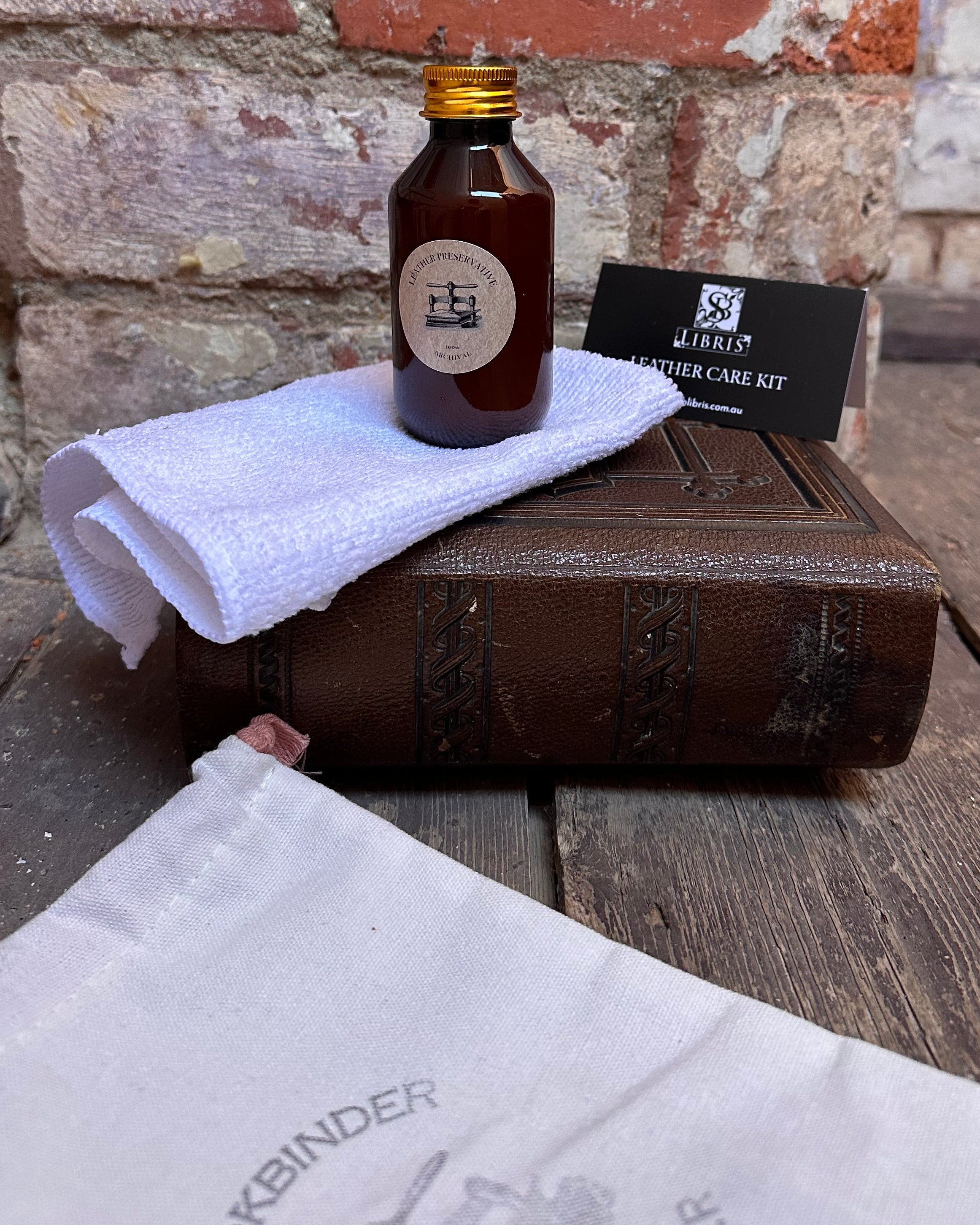 Bottle of leather preservative on a stone surface with a wooden box and white towel.