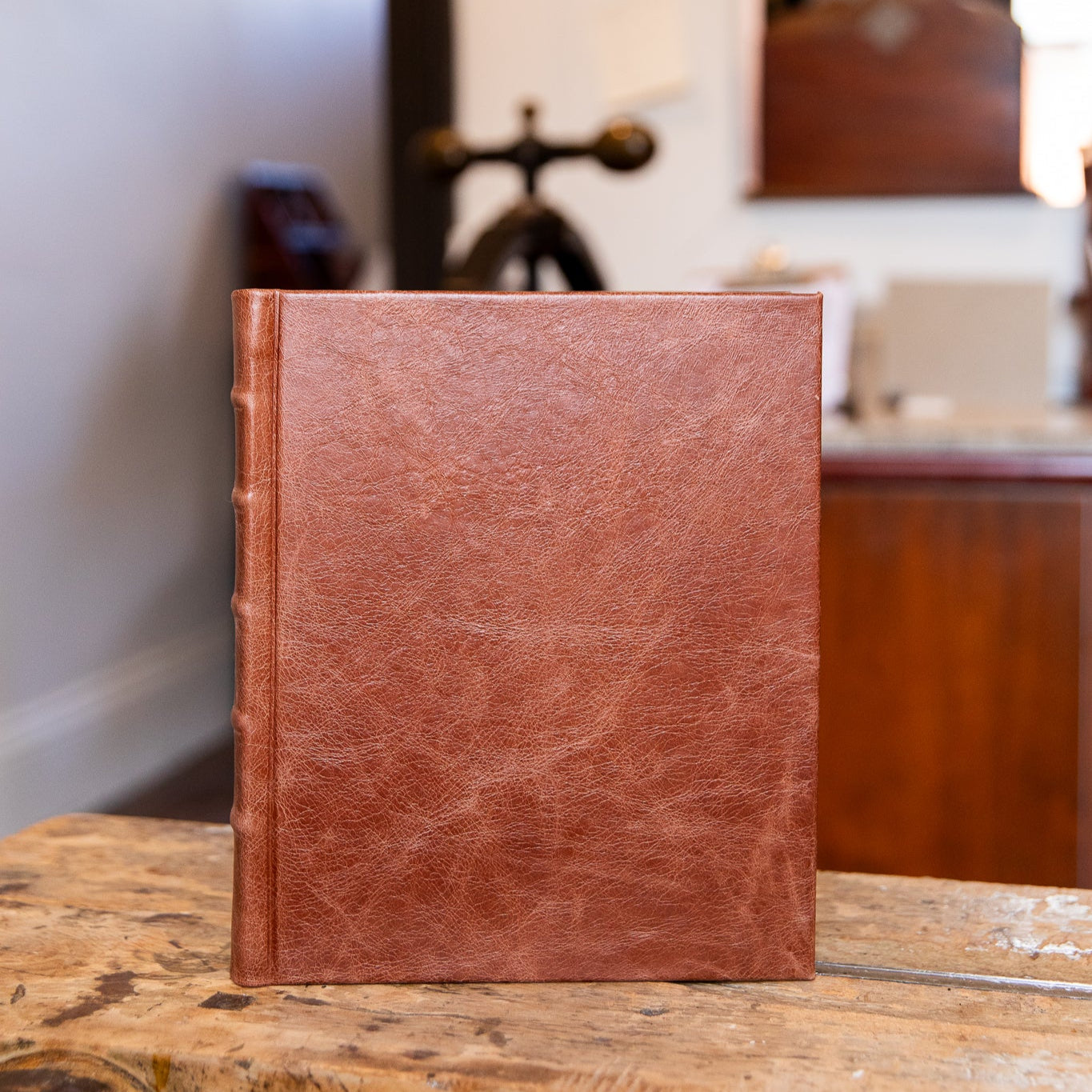 Brown leather-bound photo album on a wooden surface with a blurred indoor background