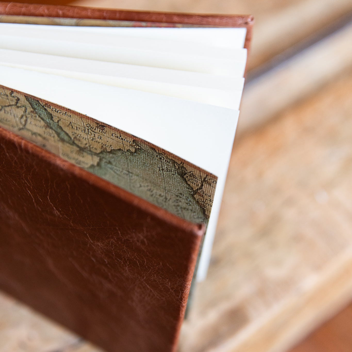 Close-up of a leather-bound book with decorative spine on a wooden surface