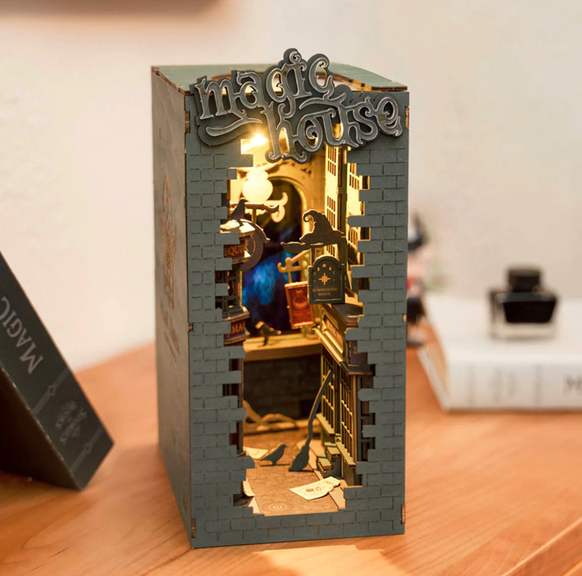 Miniature model of a house with a lit interior on a wooden surface.