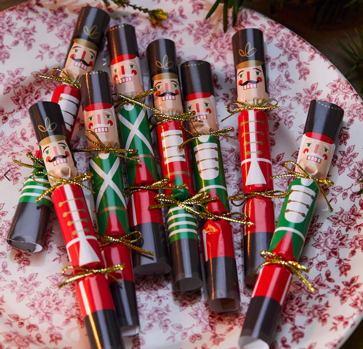 Decorative Christmas crackers with nutcracker design on a floral plate.