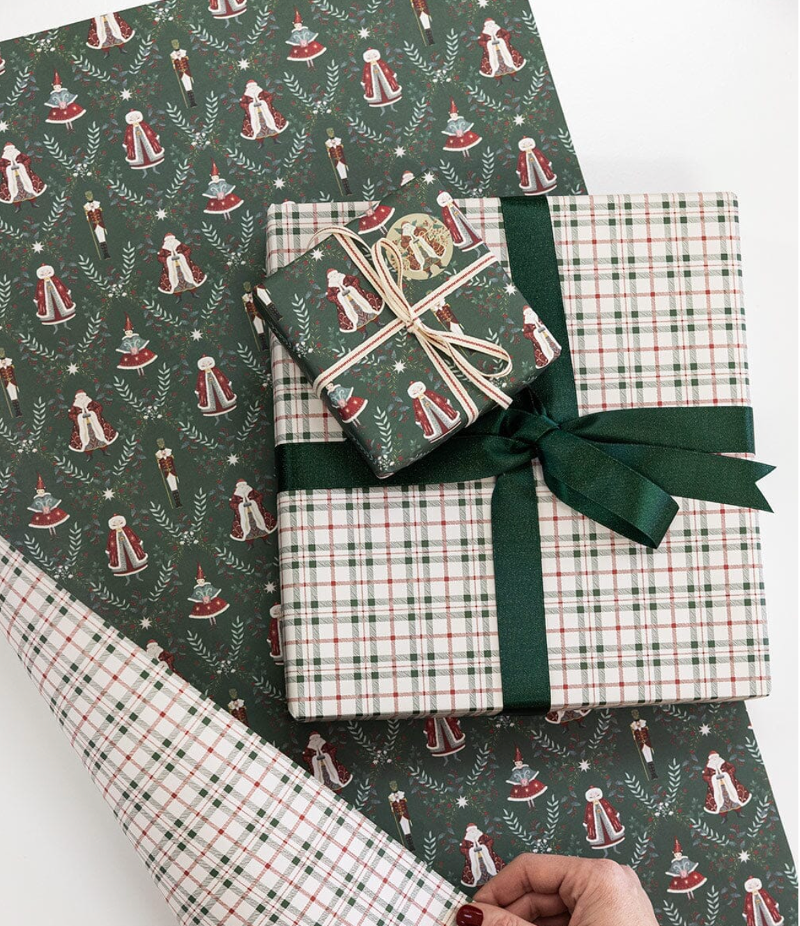 Gifts wrapped in festive paper with a green ribbon on a white background