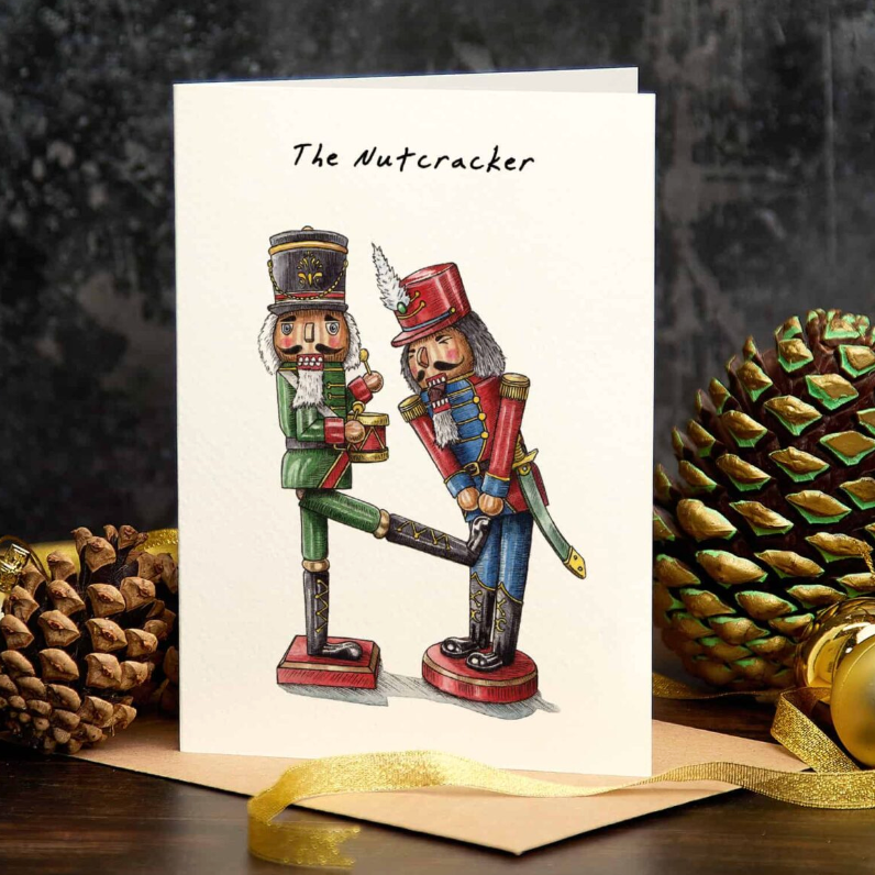 Greeting card with 'The Nutcracker' design featuring two nutcrackers and decorative pine cones and ornaments on a dark background.