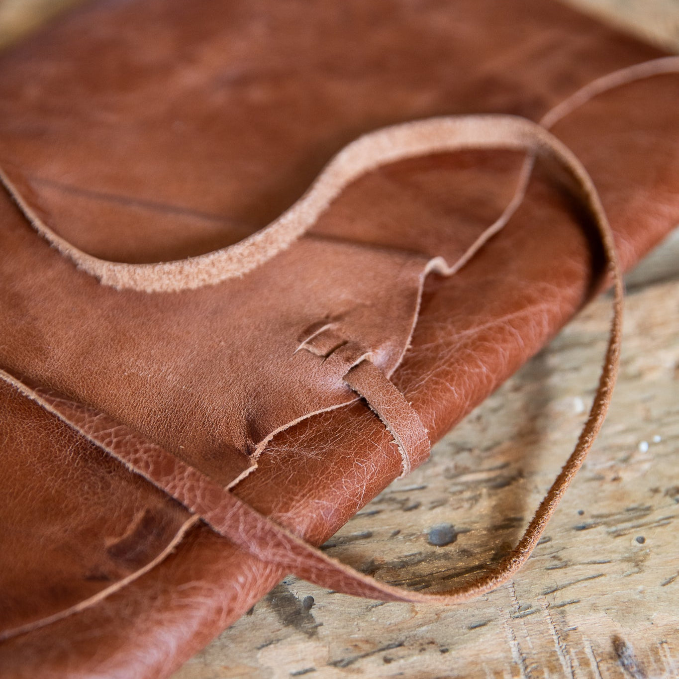 Close-up of a brown leather wrap journal on a wooden surface
