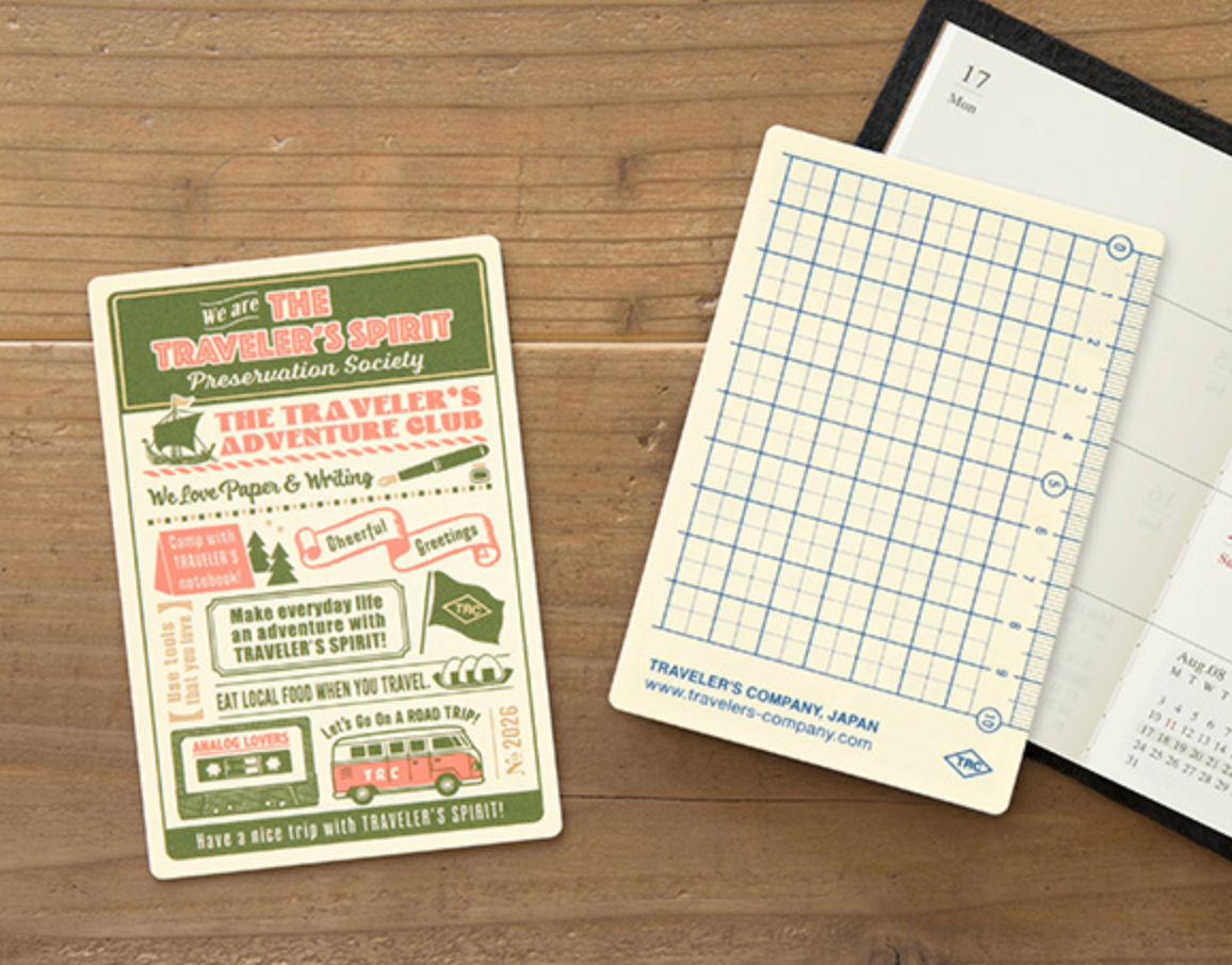Notebook with a travel-themed flyer on a wooden surface