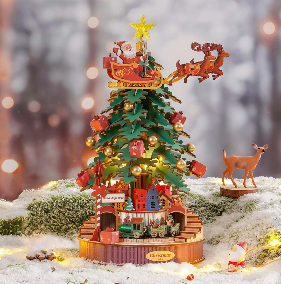 Decorative Christmas tree with Santa Claus, reindeer, and sleigh on a snowy landscape.