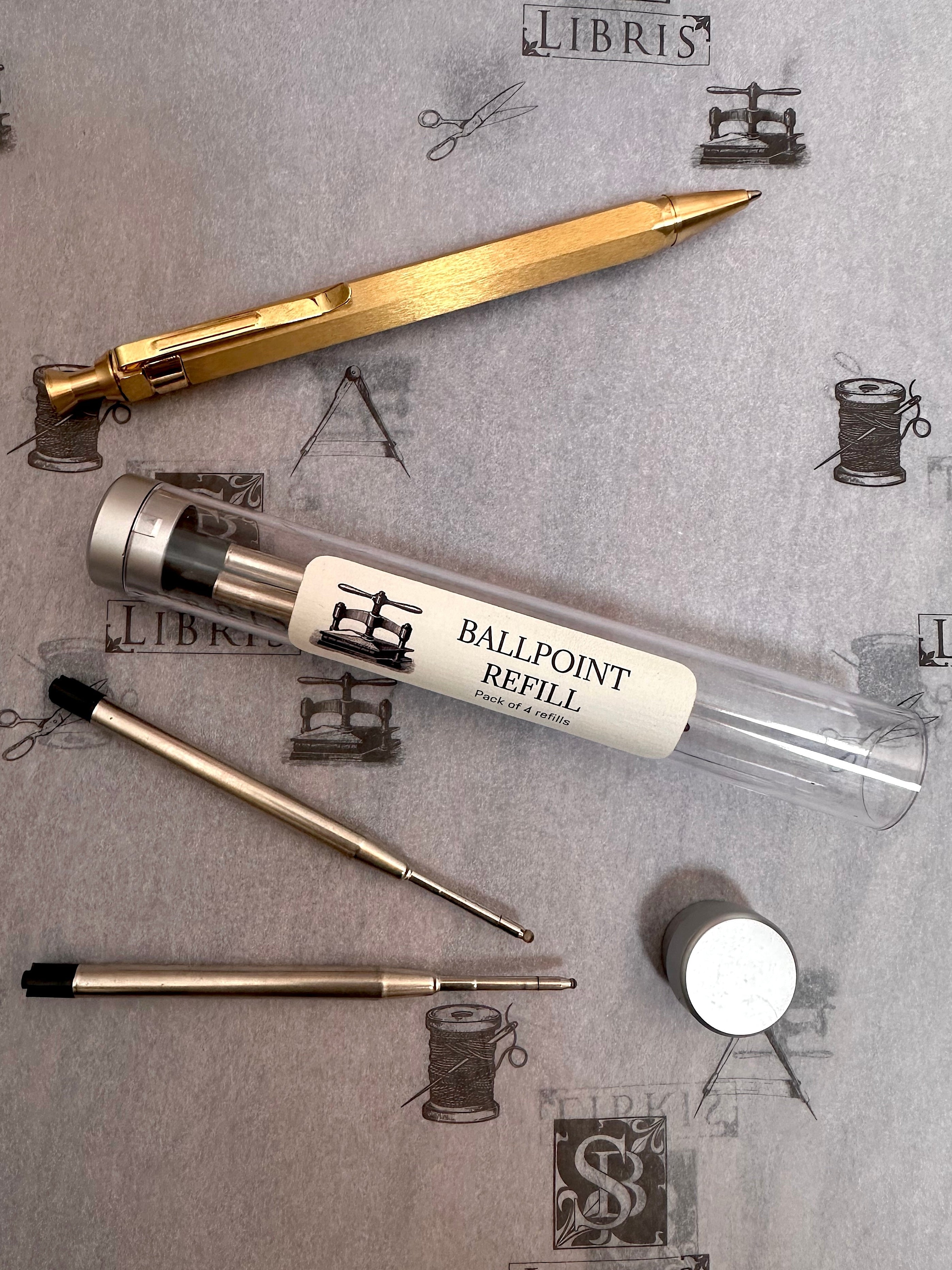 Ballpoint refill with gold pen  on a textured surface with 'Libris' branding.