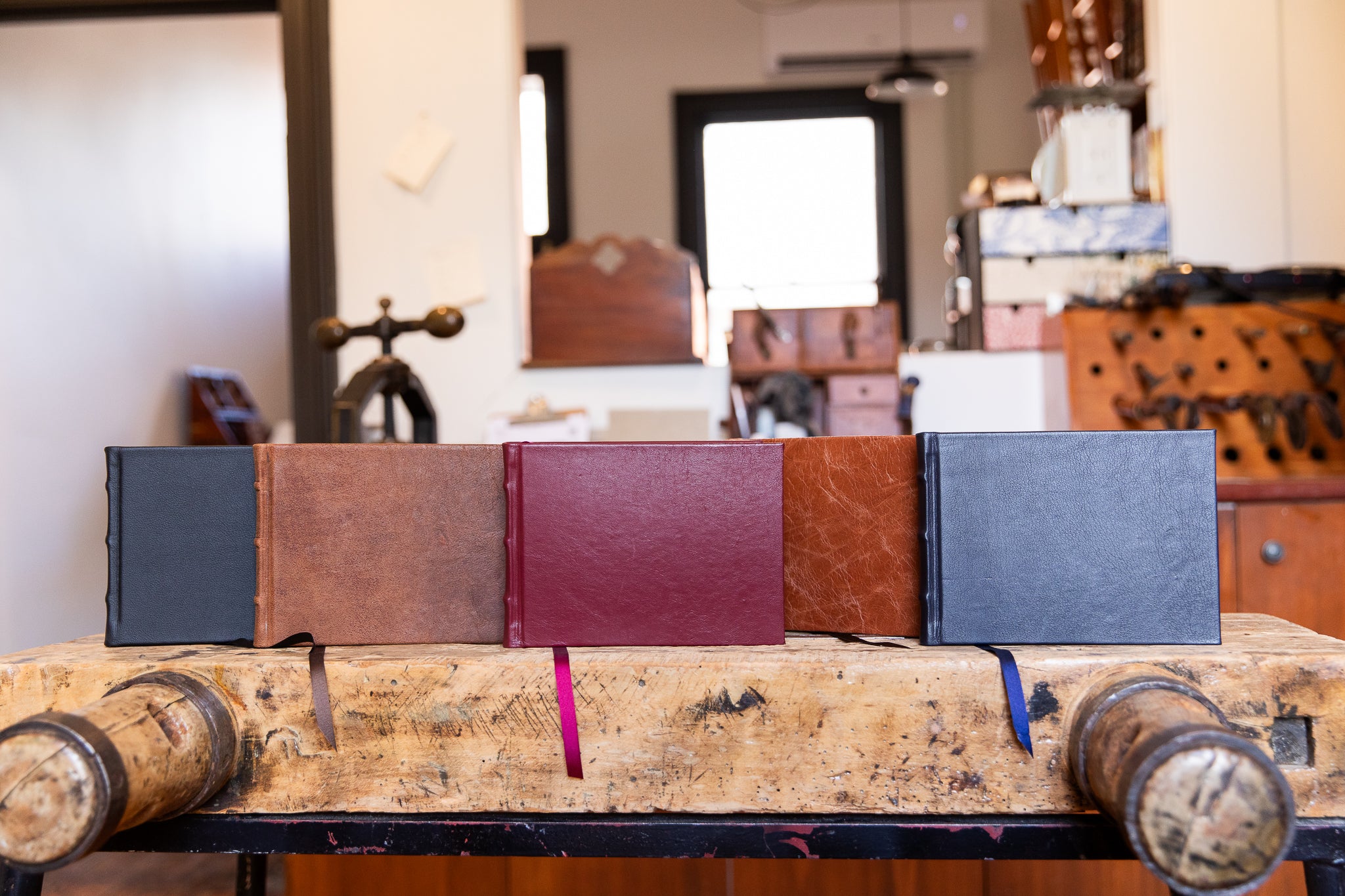 Four leather-bound books on a wooden surface with a blurred indoor background