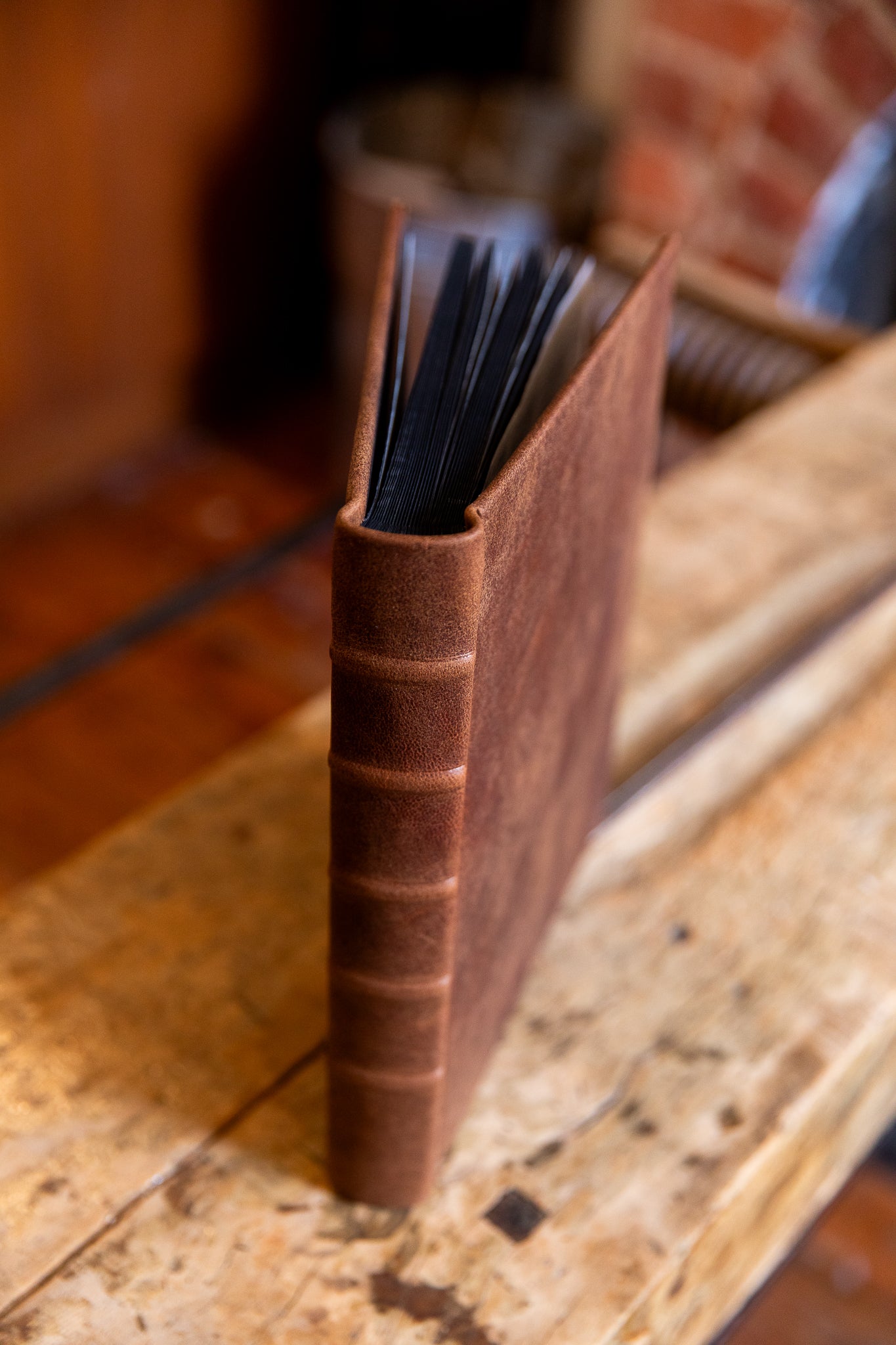 Brown leather-bound album in aged goatskin on a wooden surface with a blurred background