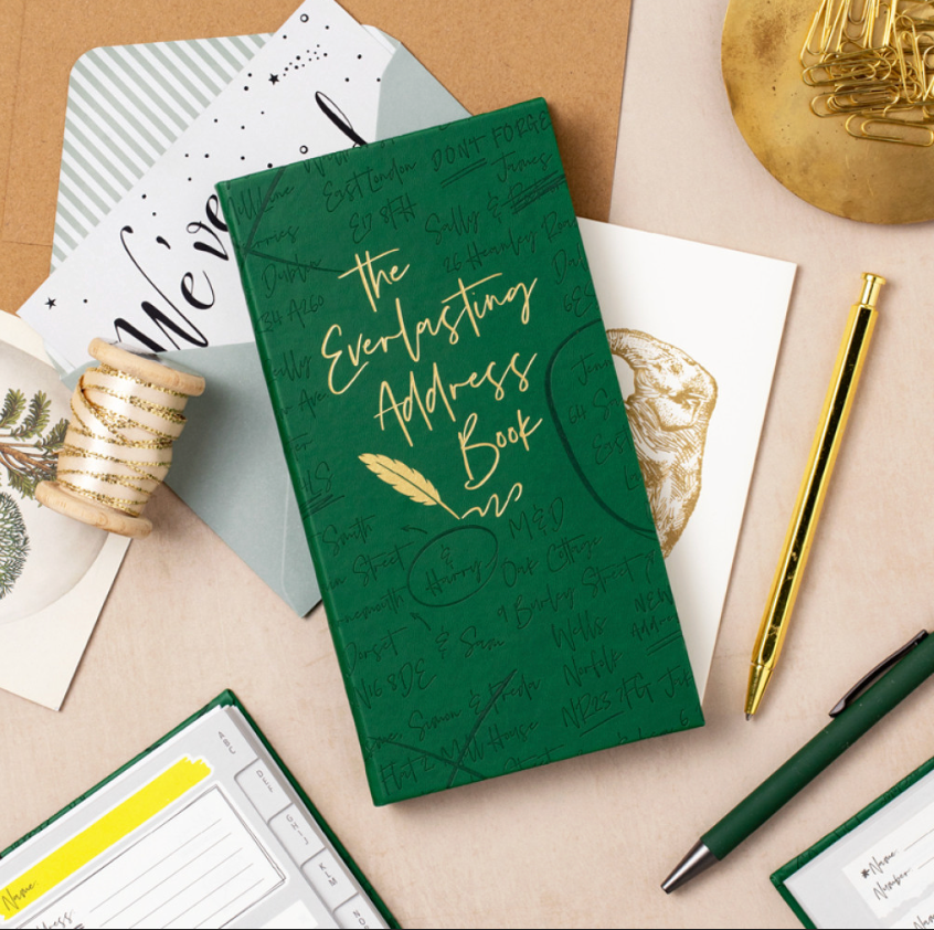 Green address book with gold text on a desk with stationery items