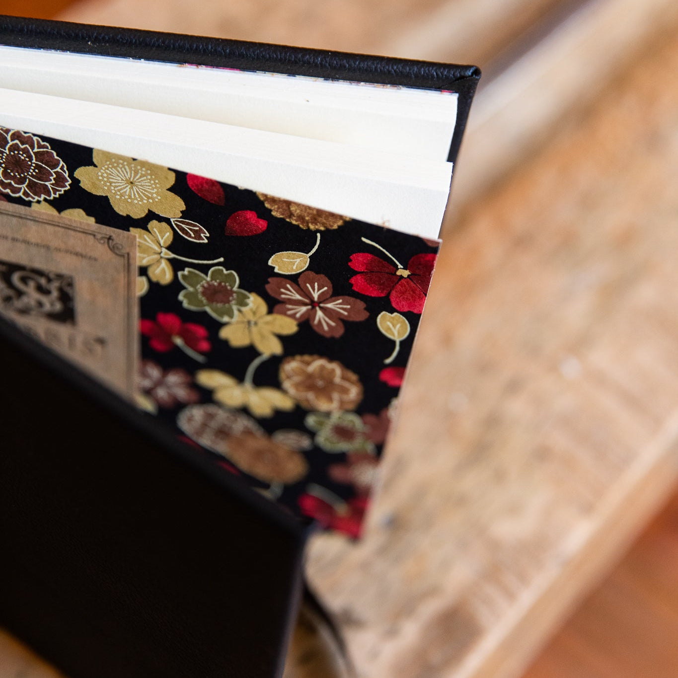 Close-up of a leather guest book with Japanese floral patterned endpapers on wooden surface