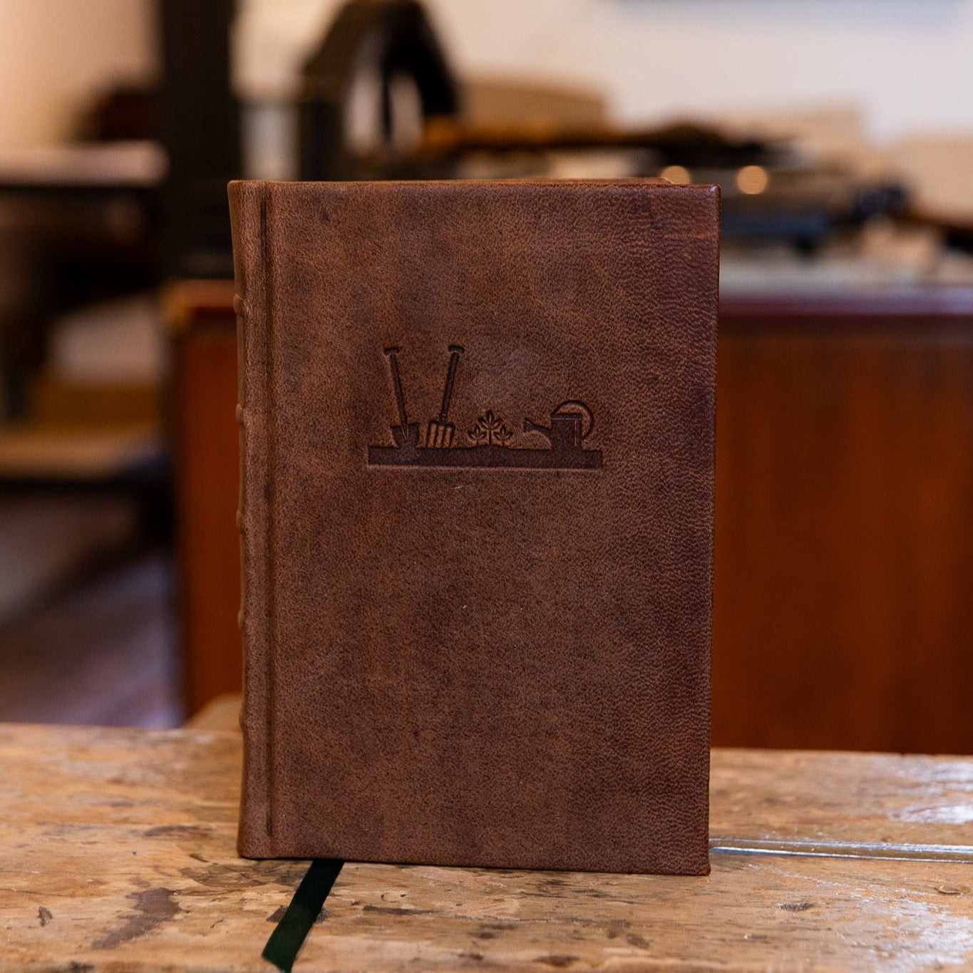 Front view of the SB Libris gardener’s journal with embossed gardening icons on a rich brown leather cover.