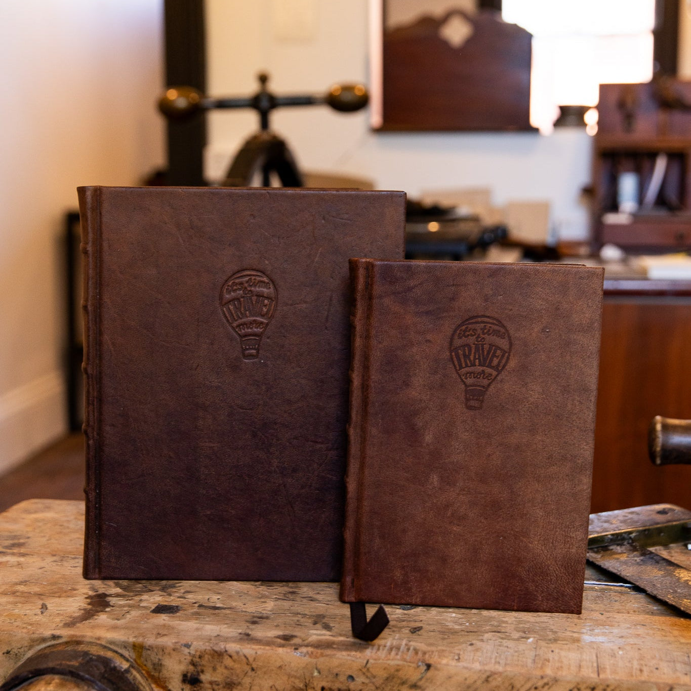 Two handcrafted leather travel journals from SB Libris — large and small — with hot air balloon embossing and brown ribbon markers.